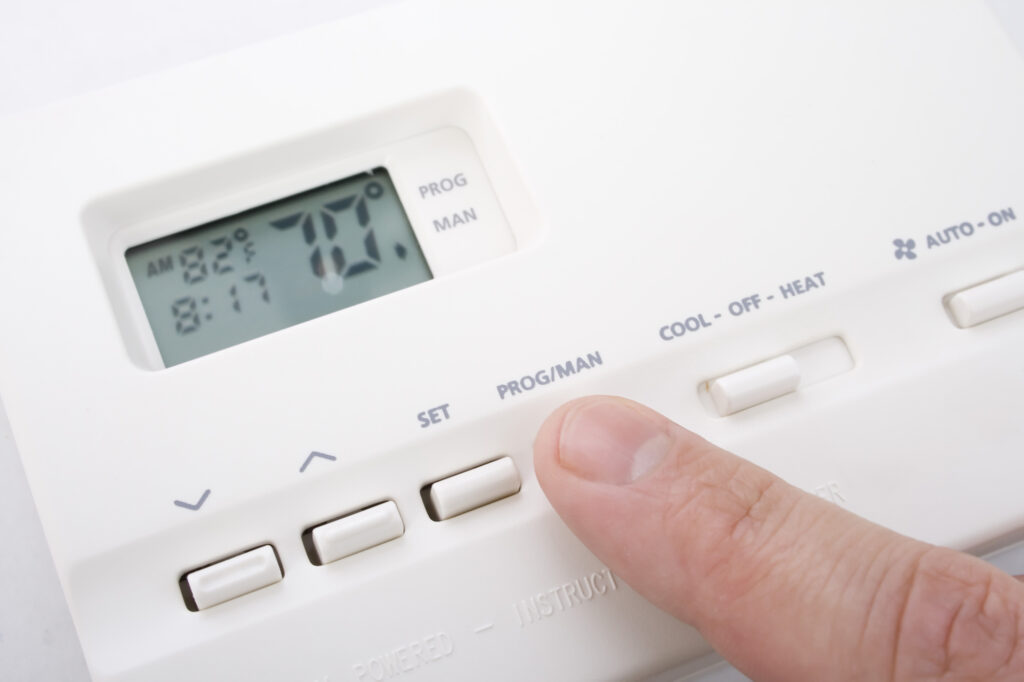 Closeup shot of male hand adjusting thermostat to 70 degrees