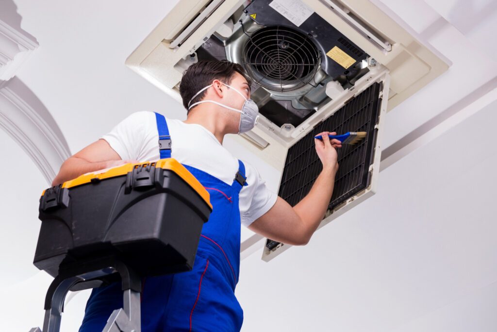 Worker repairing ceiling air conditioning unit